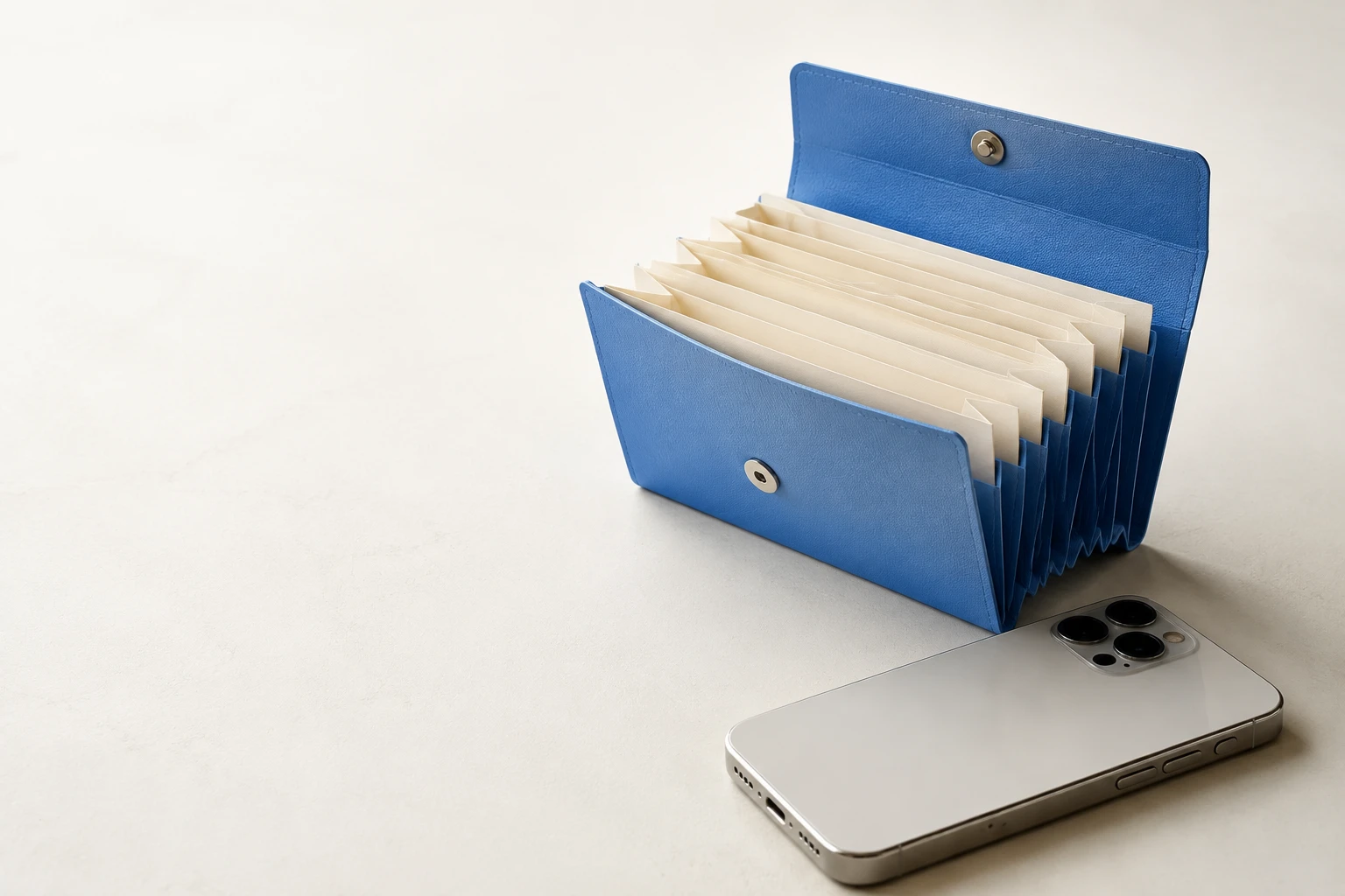 Open blue accordion file with cream papers beside a silver phone