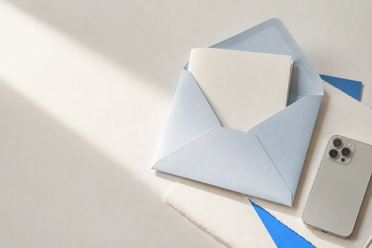 Blank cream document inside a pale blue envelope beside a silver phone